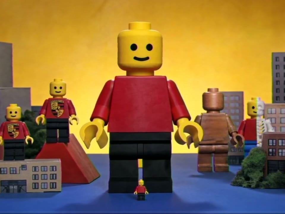 A large red Mega Figure standing over a toy city skyline, from the Think Big commercial